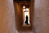 A woman in silhouette down a narrow corridor.